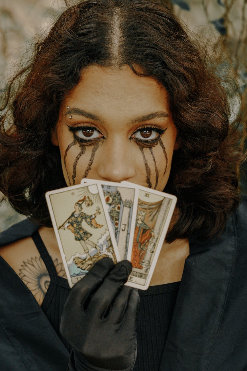 woman with creepy makeup holding tarot cards