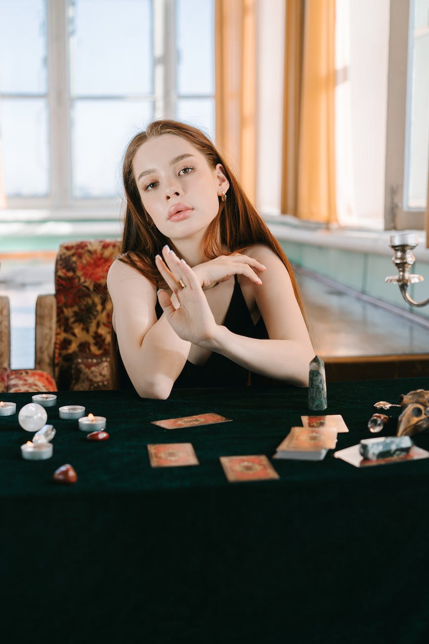 a woman sitting near the black table with tarot cards