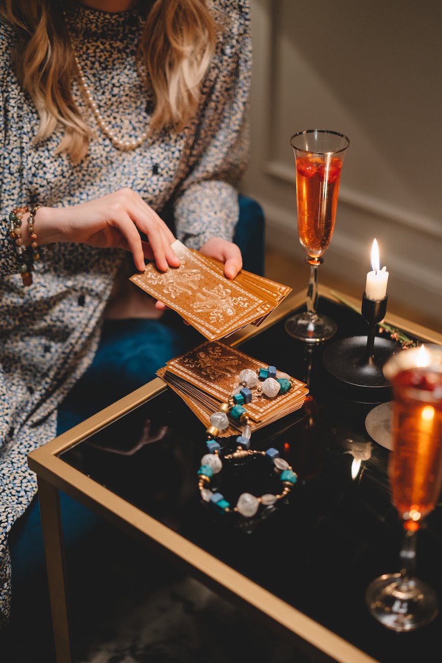 close up of woman holding a deck of tarot cards and sitting at a table with champagne glasses