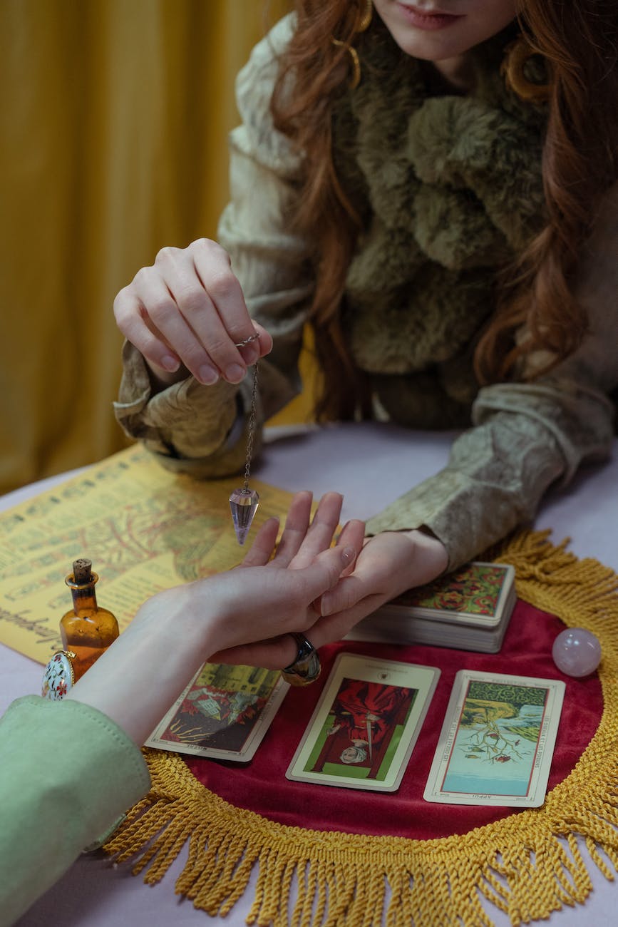 a fortune teller holding a hand of a person while reading a tarot cards
